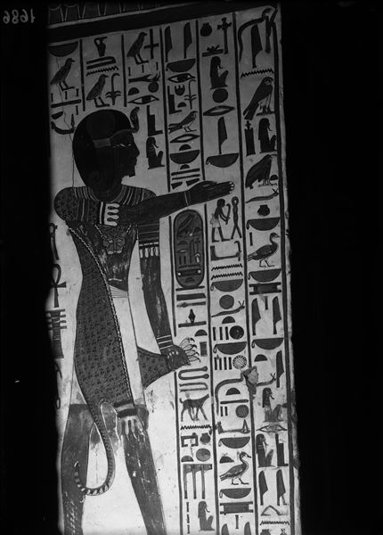 Veduta del pilastro A, lato a, della camera funeraria. Si riconosce il dio/sacerdote Iunmutef, con veste di pelle di leopardo e braccio rivolto verso la parte centrale della camera. L’iscrizione è rivolta a Osiride.