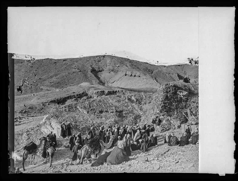 Gruppo di operai egiziani con cammelli durante gli scavi della Valle delle Regine, nei pressi dell’accampamento. Sullo sfondo, l’ingresso di quattro tombe nel settore chiamato “valletta del principe Ahmose”. Scavi Schiaparelli.