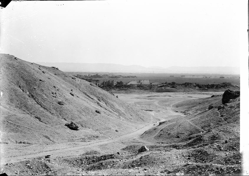 View of the plain in front of the entrance leading to the Valley of the Queens. Visible in the background, the temple of Medinet Habu built by Ramesses III. Schiaparelli excavations.