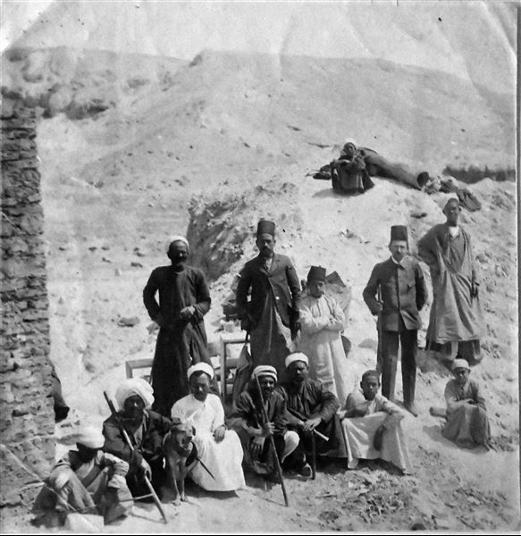 Photograph taken during excavations in the Valley of the Queens presumably in 1903, near the camp. Identifiable in the group: Francesco Ballerini, dressed in western clothing and wearing a fez on his head, and the dragoman (guide and interpreter) Bolos Ghattas, standing to Ballerini’s right. Angelo Sesana Archive. 