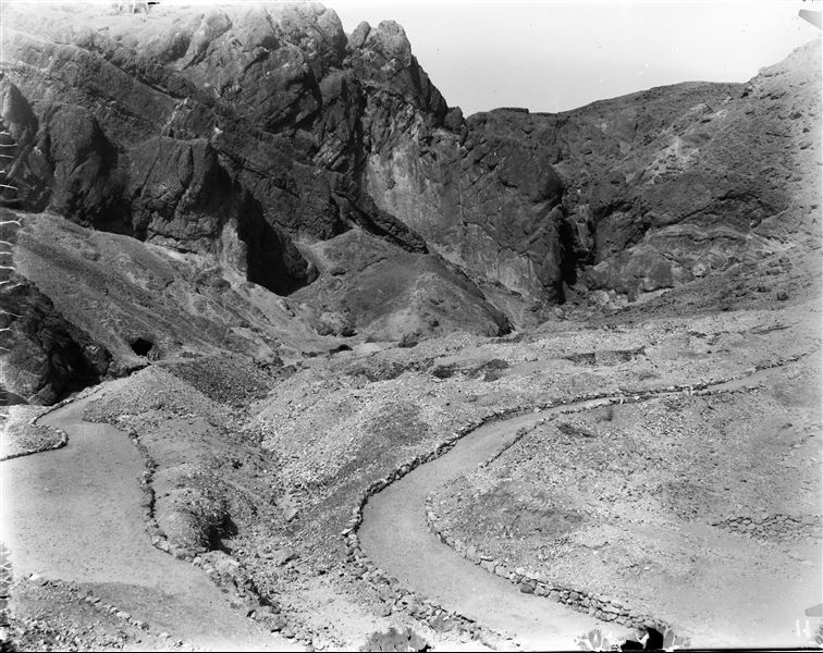 Veduta della parte finale della Valle delle Regine. Al centro, è visibile la struttura in mattoni eretta dalla Missione Archeologica Italiana per proteggere l’ingresso della tomba QV55, di Amenherkhepeshef. Accanto, vi è una tenda conica, forse un punto di appoggio per i primi lavori conservativi, ad opera del restauratore Fabrizio Lucarini. Scavi Schiaparelli. 