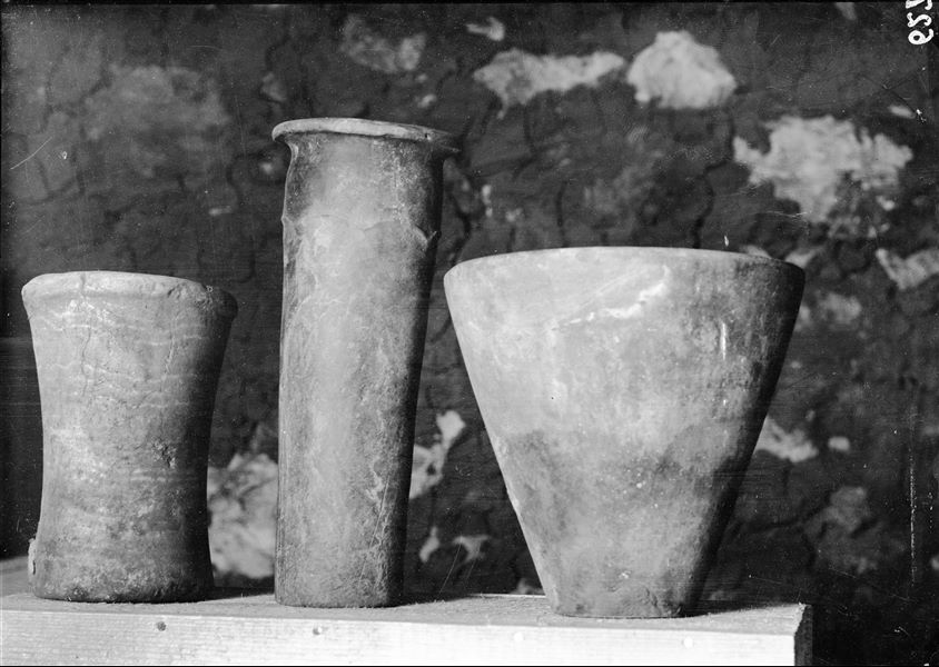 Vases found in a tomb that was reused in a later period, from the left: a cup-shaped alabaster vase (S.14105); a cylindrical terracotta vase (S.14106) and limestone bowl (S.14107). Schiaparelli excavations.
