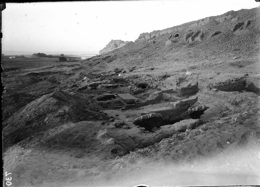 Excavations at the foot of the southern hill, western side. Remains of mud-brick structures with a barrel vault. At the top, vaults from large structures attached to the mountain can be seen. Schiaparelli excavations. 