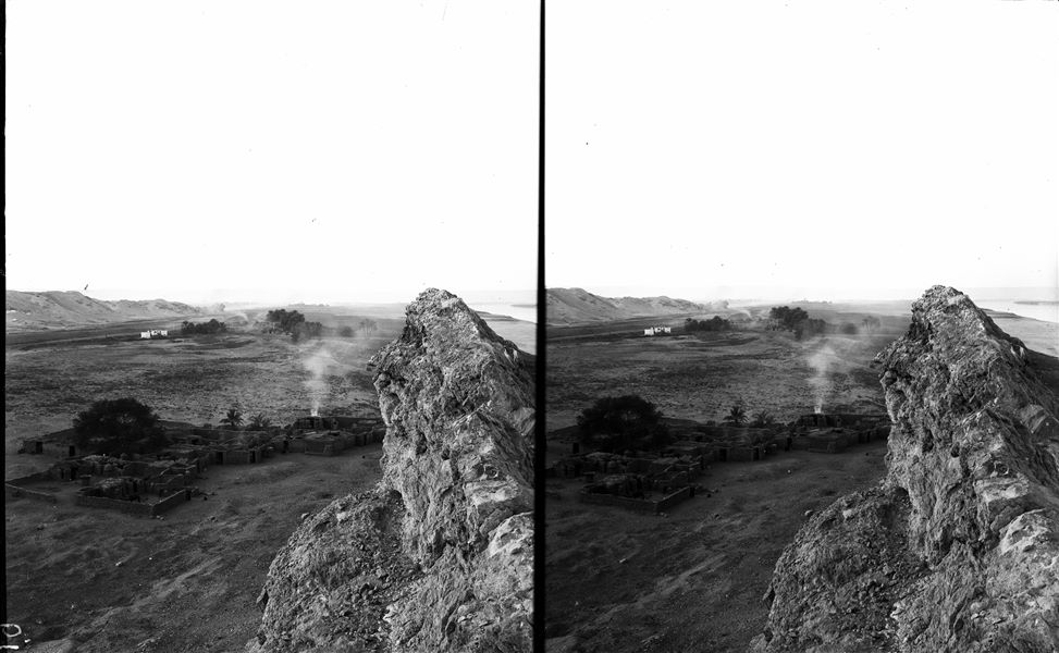 View from the northern summit of the hill. In the background on the left, the northern extension of the first hill can be seen. In the centre is a small indigenous village. The area between the two hills was partly occupied by the ancient settlement of Pathyris-Aphroditopolis. Schiaparelli excavations. 