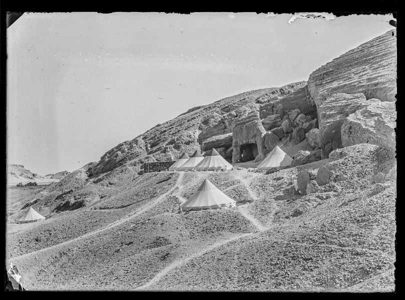  The Italian Archaeological Mission’s camp set up on a southern plateau of the first hill. In the background, the opening of a cave-tomb can be seen, with a man named Pizzio standing in the opening. Schiaparelli excavations 1914.