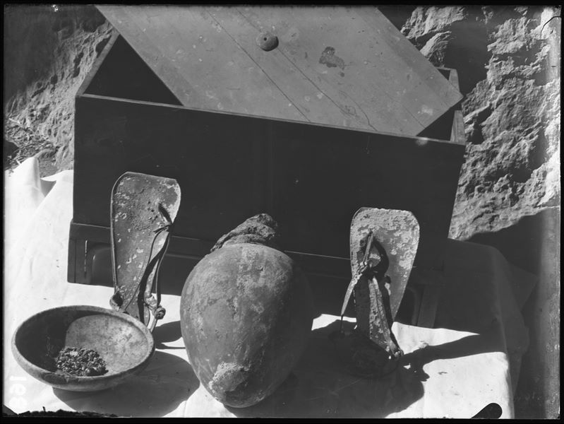 Tomb of the Unknown. Before being packed for transport, the objects were inventoried and photographed, often grouped together. Visible in the picture: a chest with a lid (S.13986); a stone bowl (S.14039); a terracotta vase with a mud cap (S.13996) and a pair of leather sandals (S.14043). Schiaparelli excavations. 