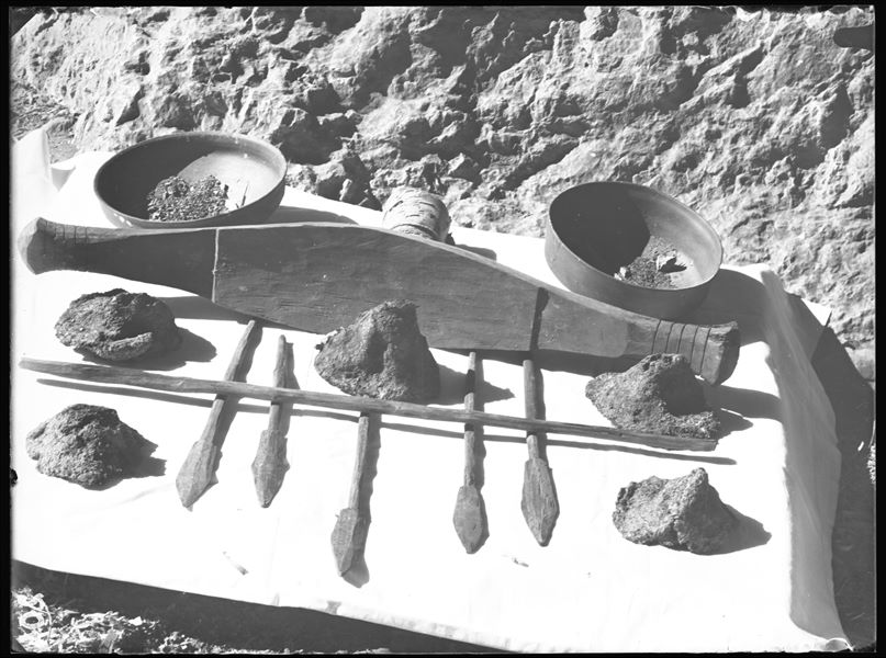 Tomb of the Unknown. Before being packed for transport, the objects were inventoried and photographed, often grouped together. Visible in the picture: a model boat (S.14047) with oars and a pole (S.14048); five loaves of bread (S.14051,2,3,4,5); two terracotta bowls (S.13995 and S.13992) and a strip of rolled up cloth (S.14050). Schiaparelli excavations. 