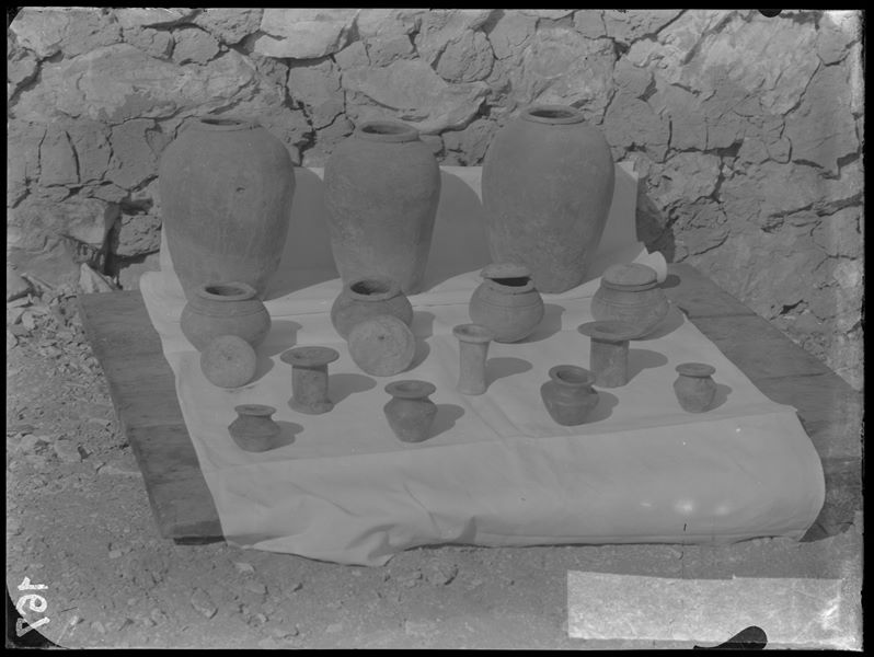 Tomb of Iti and Neferu, Neferu’s grave goods. Before being packed for transport, the objects were inventoried and photographed, often in groups. Visible in the picture: three large terracotta vases (S.13031, 2, 42); four globular terracotta vases with lids (numbered between S.13049 and S.13058); four miniature terracotta vases (numbered between S.13059 and S.13074); two small cylindrical black terracotta vases (S.13075,6) and a small cylindrical alabaster vessel (S.13023). Schiaparelli excavations. 