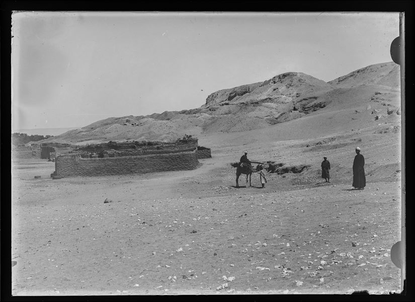  Excavation area near Gebelein, with some Egyptian men, one of whom is on a camel. Slightly visible in the background, some areas where excavations were continuing. 