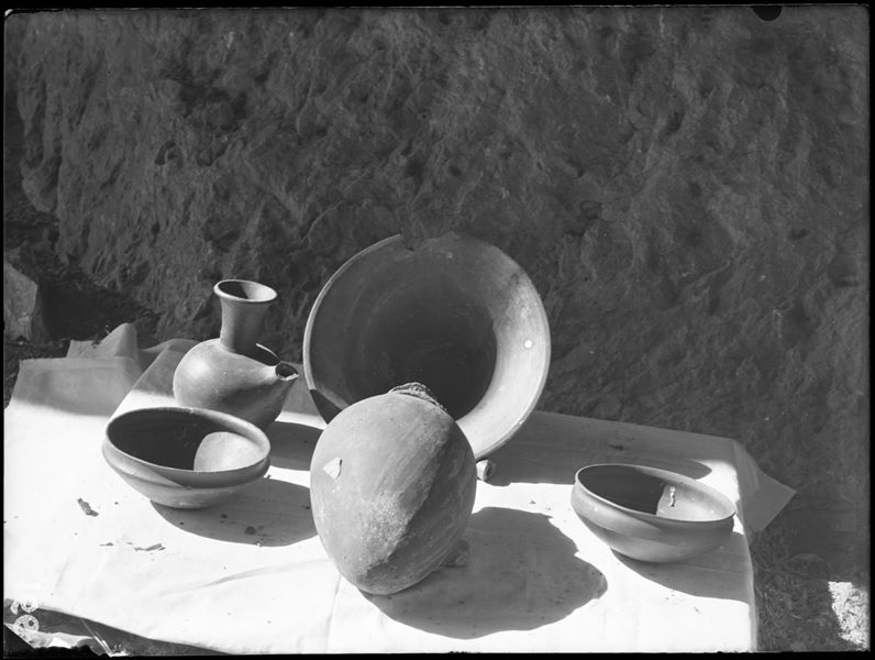 Tomba di Ignoti. Prima di essere imballati per il trasporto, gli oggetti venivano inventariati e fotografati, spesso riuniti in gruppi. Nell’immagine sono visibili: acquamanile in terracotta (S.13990 catino, S.13991 brocca); vaso in terracotta con tappo di fango (S.13997); due ciotole in terracotta (S.13992 e S.13994). Scavi Schiaparelli. 