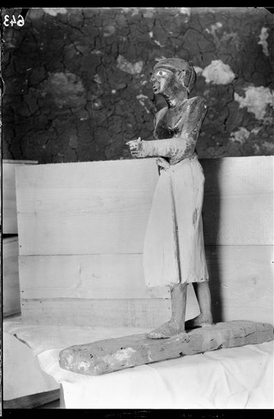 Tomb of Ini. Before being packed for transport, the objects were inventoried and photographed, often gathered in groups. The picture shows the preparation of packing special crates to house the materials. Visible in the foreground is a small wooden painted statue of the deceased Ini. (S.13269). Schiaparelli excavations.  