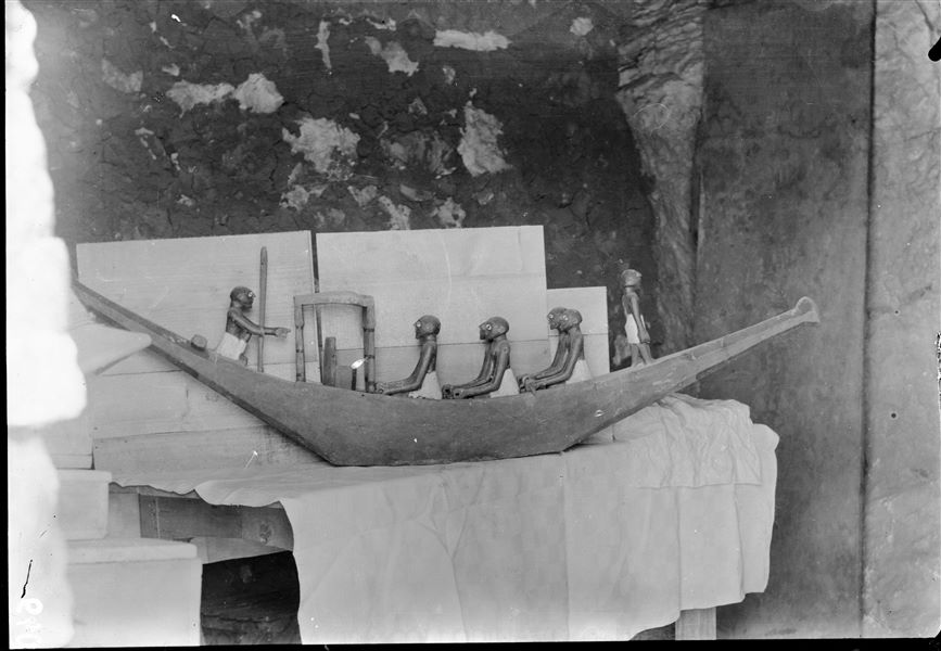 Tomb of Ini. Before being packed for transport, the objects were inventoried and photographed, often gathered in groups. The picture shows the preparation of packing special crates to house the materials. In the foreground, a model of one of the two boats with a captain, helmsman and rowers (S.13273). Schiaparelli excavations.  