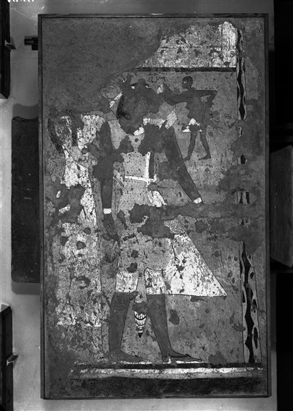 Tomba di Iti e Neferu. Allestimento museale. Nel corso della campagna di scavi del 1911, procedendo con le operazioni di sterro della tomba, emersero preziose pitture a tempera che, oltre all’aspetto funerario, documentano gustose scene di vita quotidiana in un contesto agricolo. Le pitture verranno poi staccate e portate in Museo nel corso della campagna del 1913-14, come documentato da queste immagini. La fotografia mostra la parete di fondo, lato destro, della cappella per il culto dei defunti, con la rappresentazione dei coniugi in tenero atteggiamento in candidi abiti da cerimonia. Scavi Schiaparelli. (S.14354/10)