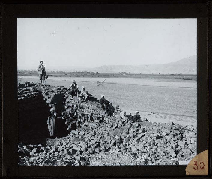 Giulio Farina (in piedi), Giovanni Marro (seduto) e alcuni egiziani in posa su alcune rovine sulla Collina Sud, vicino al fiume Nilo, a Gebelein. Scavi Farina.