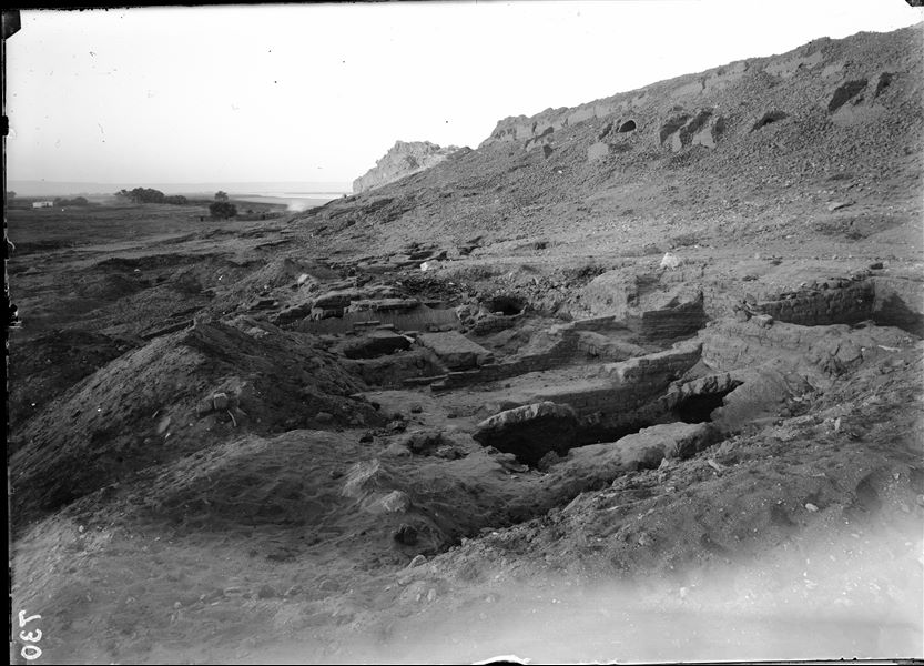 Excavations at the foot of the southern hill, western side. Remains of mud-brick structures with a barrel vault. At the top, vaults from large structures attached to the mountain can be seen. Schiaparelli excavations. 