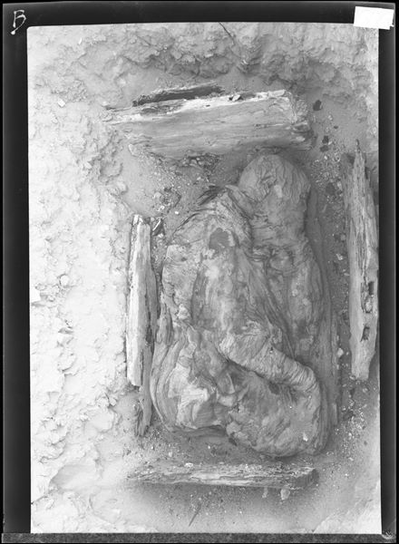 Scattered burials in the desert area north of northern hill. The little remains of the wooden box preserve an intact mummy in a contracted position and carefully bandaged. Farina excavations. 