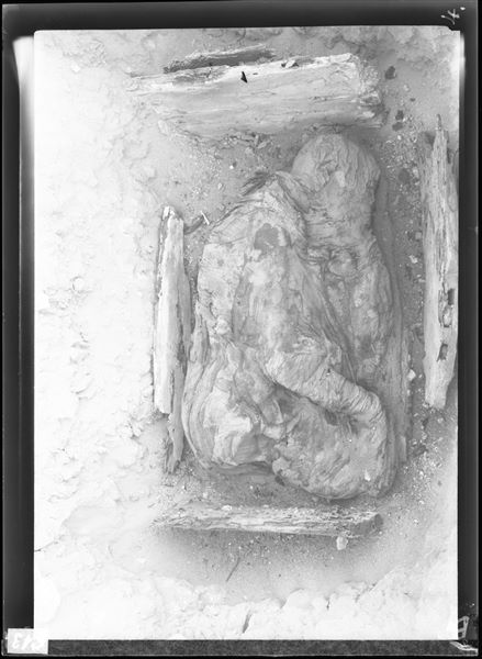 Scattered burials in the desert area north of northern hill. The little remains of the wooden box preserve an intact mummy in a contracted position and carefully bandaged. Farina excavations. 