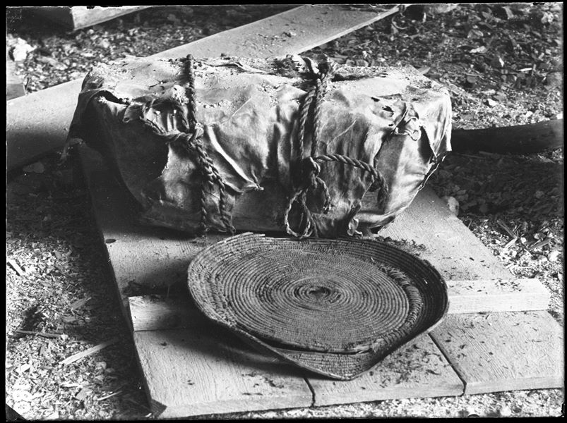 Burial called "a mummy bundle". The body, in a tightly contracted position, was wrapped in cloth or animal skins, then firmly tied with ropes or cloth bands. The "bundle" was then usually placed in a short rectangular coffin. Next to it was a straw dish. Schiaparelli excavations.  