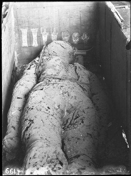 Tomb of Iti, “Chief of expeditions to the desert". The picture shows the cedar wood coffin with the mummy of Iti, at the time of its discovery by the researcher Virginio Rosa. The mummy, laid on its back, has individually wrapped limbs. Schiaparelli excavations. (S.13719) 