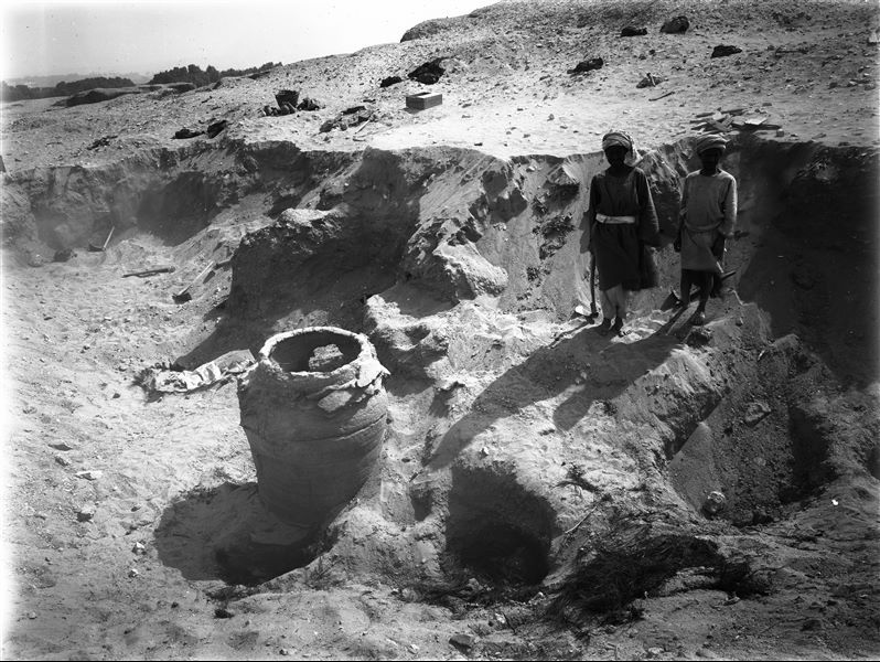 Scattered burials on the eastern slopes of the northern hill. During a work break, the large burial vase was photographed with two very young workers beside it, perhaps to illustrate its considerable size. In the background, near a modern basket, there are numerous vases found scattered among the disturbed burials. Farina excavations. 