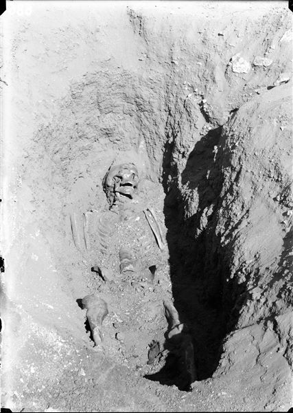 Burials in the plain to the east of the northern hill. The image displays the scene from the previous photograph C00687, after the removal of the ceramic fragment that covered the deceased’s skull. Schiaparelli excavations. 