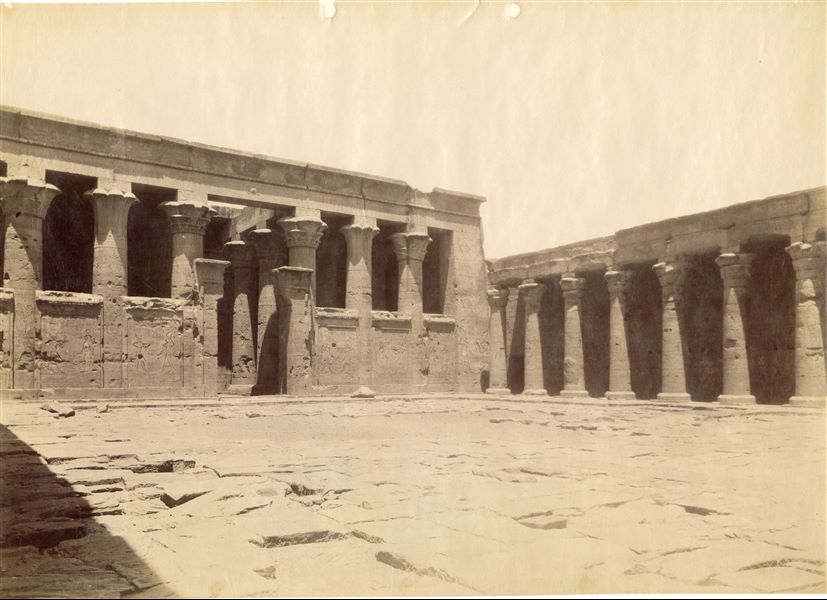 Photograph of the large colonnade of the Temple of Horus at Edfu seen from the southwest, with a glimpse of the colonnade on the eastern side of the courtyard in front of it. Based on the calligraphic style of the caption, it is possible to attribute the image to Antonio Beato. 