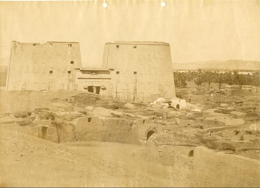The photograph shows the 19th century village of Edfu in the foreground, and the façade of the Ptolemaic temple in the background. Based on the calligraphic style, the work can be attributed to Antonio Beato. 