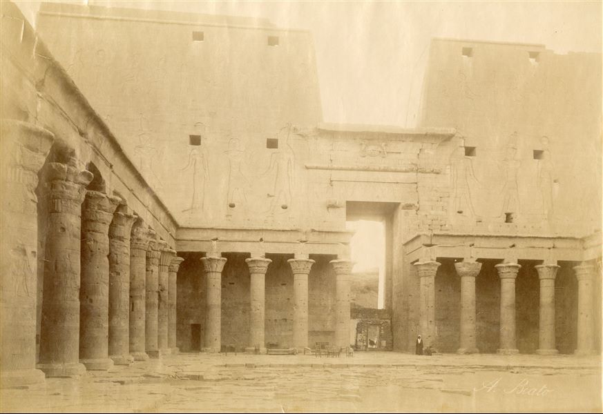 Veduta della parete interna del pilone d'accesso al tempio di Horus a Edfu, con una parte del colonnato del cortile. In basso, la firma dell’autore.  