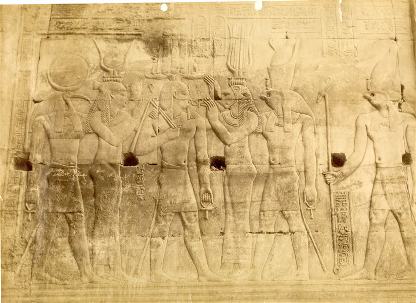 La fotografia presenta una scena sacra dalle pareti interne del tempio di Sobek e Haroeris a Kom Ombo, un bassorilievo posto nell'area consacrata a Horus. Tolomeo XII riceve l'Ankh e la corona dagli dei Thot, Bastet, Iside al cospetto di Horus e Ra.  