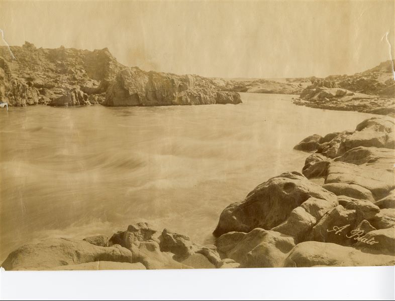 The image shows the Nile at the First Cataract, near Aswan. The author's signature has been placed at the bottom right. 