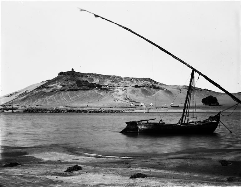 View of the northern slope of the Qubbet el-Hawa rock-cut tombs, photographed from the other side of the Nile. Halfway up the hill we can see the mission’s camp. In the center, the excavation of an ascending ramp, to be placed between the ramps of Khunes and Sarenput I. Schiaparelli excavations.