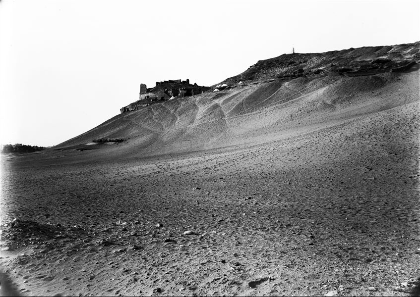 Veduta del versante settentrionale della necropoli rupestre della Qubbet el-Hawa. Si riconosce, a mezza costa, l’accampamento della missione. Scavi Schiaparelli.