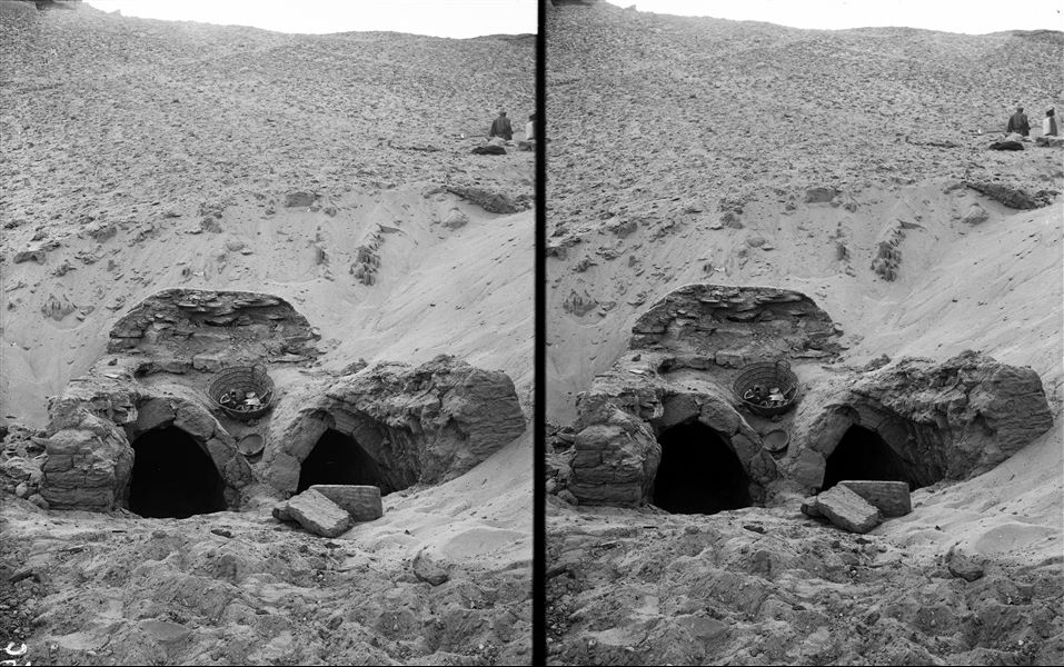 Excavation of some funerary structures, during the excavations in the Qubbet el-Hawa. In the basket, some human remains are visible.  Schiaparelli excavations.