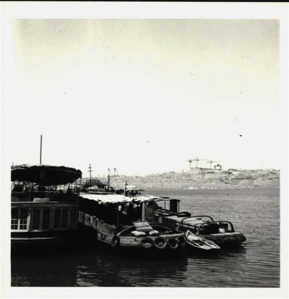Photograph taken in the area of the site of Ellesiya, when Lake Nasser had already formed and was full. In the foreground, there are three boats for the transport and accommodation of the people who were working on the rock-cut chapel of Ellesiya. In the background, there is a construction site in action. 