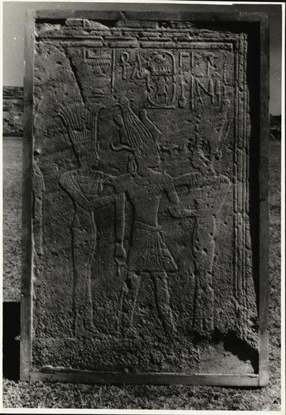Storage at Wadi es-Sebua, one of the 66 blocks from the rock-cut chapel of Ellesiya stored waiting to be transported to Turin, after the United Arab Republic decided to gift the rock-cut chapel to the Italian Republic. Wall to the left of the entrance to the transverse chamber, with depictions of the two gods of the Aswan cataract, Anuket and Satet, with the Pharaoh in the centre.  