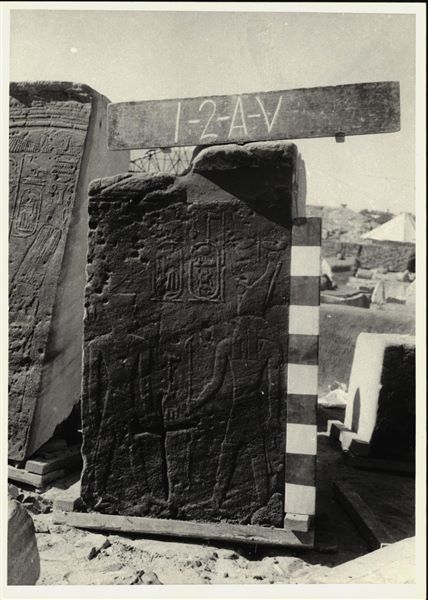Storage at Wadi es-Sebua, one of the 66 blocks from the rock-cut chapel of Ellesiya stored waiting to be transported to Turin, after the United Arab Republic decided to gift the rock-cut chapel to the Italian Republic. Wall to the left of the entrance, depicting Tuthmosis III and the god Horus of Baki. A Christian cross has been engraved in the middle of the scene.