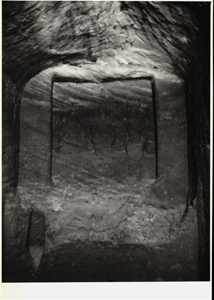 Photograph of the back niche in the rock-cut chapel of Ellesiya, where the statues of deities and the pharaoh are located; depicting Horus of Miam, the goddess Satet, and in the centre, the ruler Tuthmosis III. The photograph was taken in the rock-cut chapel’s original location in Nubia, shortly before the Nile waters would begin to rise due to the construction of the Aswan Dam, which would flood the area. Photograph taken in the mid-1960s, shortly before the rock-cut chapel was moved. Note the original floor, which was not saved.

