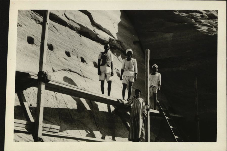 Photograph of four workers hired to work in the rock-cut chapel-moving team. The rock-cut chapel was cut into 66 blocks and reconstructed inside Museo Egizio in Turin, donated by the United Arab Republic to the Italian Republic. 
