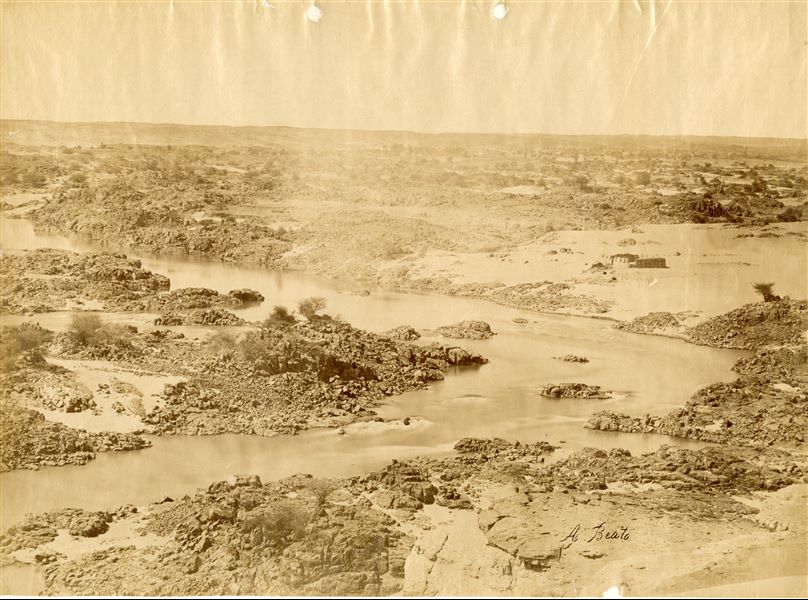 The photograph shows a view of the panorama and the rocks emerging from the Nile at the height of the Second Cataract. Nowadays, the Second Cataract has been submerged by Lake Nasser, created as a result of the construction of the Aswan Dam in the 1960s. The author's signature is visible at the bottom right. 