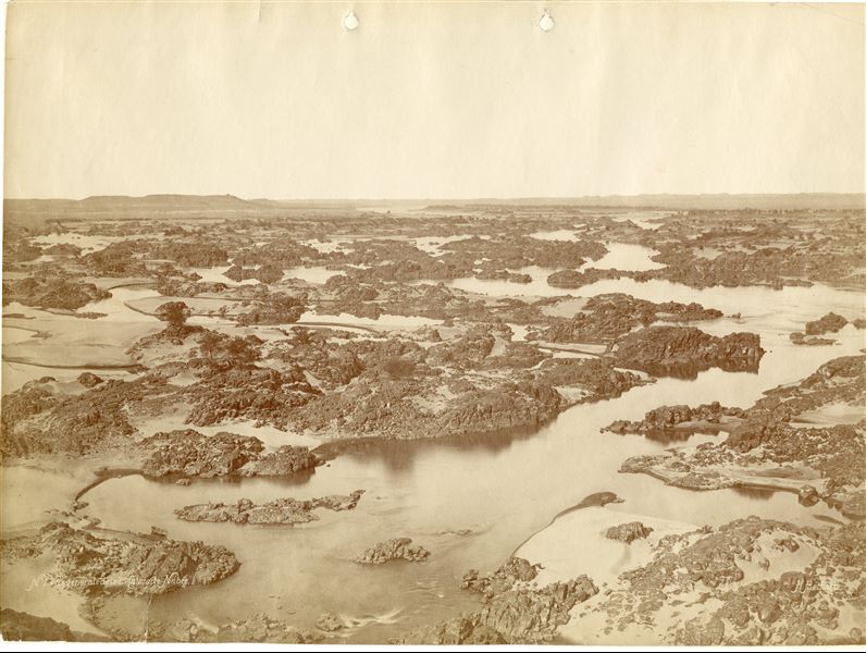 The photo shows the winding course of the Nile at the height of the Second Cataract, a barrage of rocks almost impossible to pass by boat. Nowadays, the Second Cataract has been submerged by Lake Nasser, created as a result of the construction of the Aswan Dam in the 1960s. The author's signature is visible at the bottom right. 
