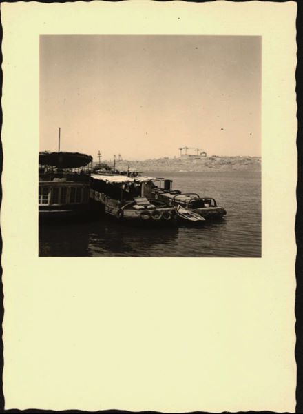 Photograph taken in the area of the site of Ellesiya, when Lake Nasser had already formed and was full. In the foreground, there are three boats for the transport and accommodation of the people who were working on the Temple of Ellesiya. In the background, there is a construction site in action. 