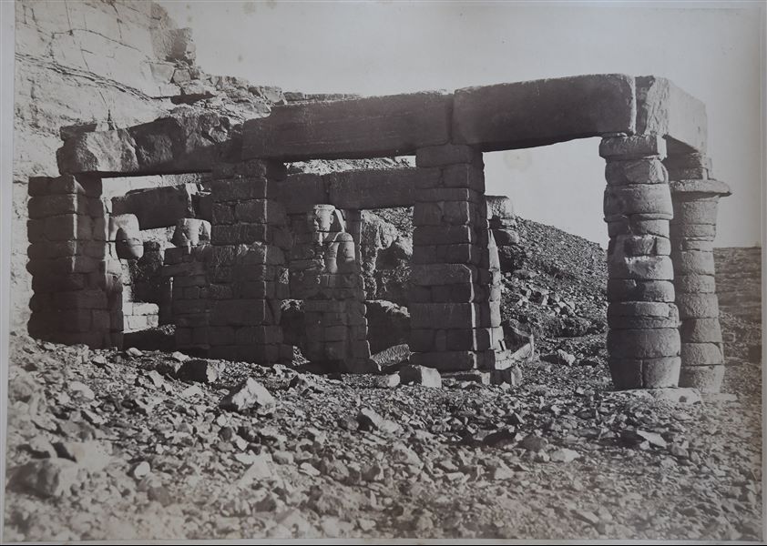 La fotografia mostra le rovine del lato settentrionale dell’ambiente con colonne del tempio di Gerf Hussein, costruito da Ramesse II in onore di Ptah, si vedono ancora alcune statue colossali del faraone Ramesse II addossate ai pilastri. In basso, la fotografia risulta sfocata. La firma dell’autore è posta in basso.