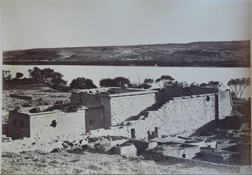Photograph of the Temple of Kalabsha in its original location in Nubia. Behind the temple stretches the Nile. The author's signature is at the bottom right of the image. The temple was moved following the construction of the Aswan Dam and the resulting formation of Lake Nasser, which would have submerged it.  The temple was then re-erected in the late 1960s at New Kalabsha, a location on higher ground not far from Aswan. The author's signature is visible at the bottom right.  