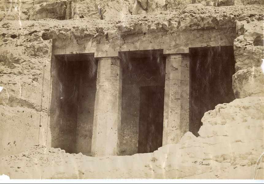 The photograph shows the access to the rock-cut tomb (no. 2) of the governor Amenemhat known as Ameny, in the necropolis of Ben Hassan. The author's signature is at the bottom right. 