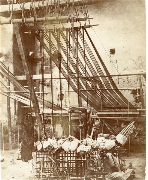 The photograph shows a man operating a loom in an Egyptian textile workshop, with a child sitting in front of the loom. The author's signature is at the bottom right. 
