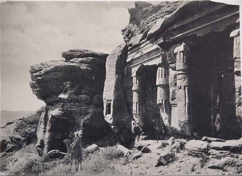 Veduta delle cappelle rupestri presso Gebel Silsila costruite dai faraoni Ramesse II e Merenptah. Un locale posa a dorso di dromedario.