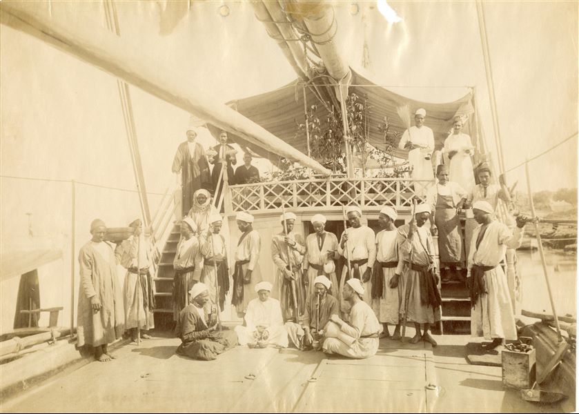 The photograph depicts a group of people on a cruise ship, presumably the service staff, with musicians and caretakers identifiable among the group.  