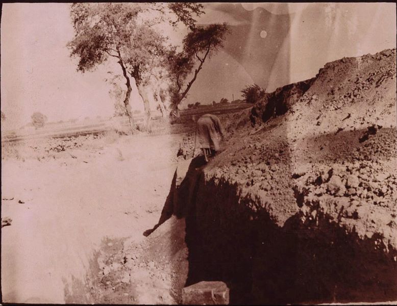 Photograph of a trench during excavations in Heliopolis by the Italian Archaeological Mission, probably in the area of the temenos. The obelisk of Sesostris I can be made out in the background. Schiaparelli excavations.
