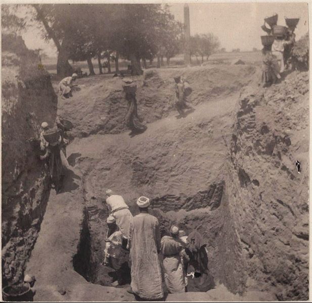 Area del santuario del sole, durante i lavori di scavo, accanto a strutture abbandonate con resti di case arabe. Sullo sfondo il lato est dell’obelisco di Sesostri I. Scavi Schiaparelli.