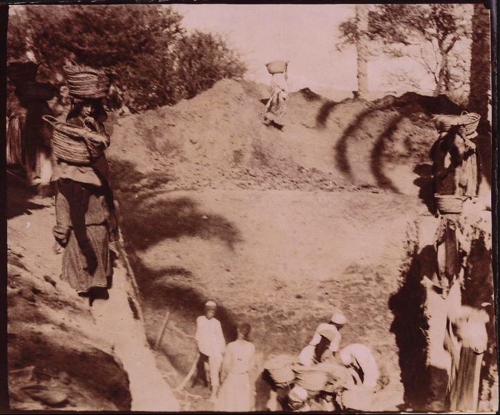 Grande trincea di scavo a ridosso di un muro, che si trova oltre il cumulo di terra smossa. Si tratta forse degli scavi nel giardino di Latif, un signore egiziano che a Eliopoli possedeva una casa e un terreno. Scavi Schiaparelli.